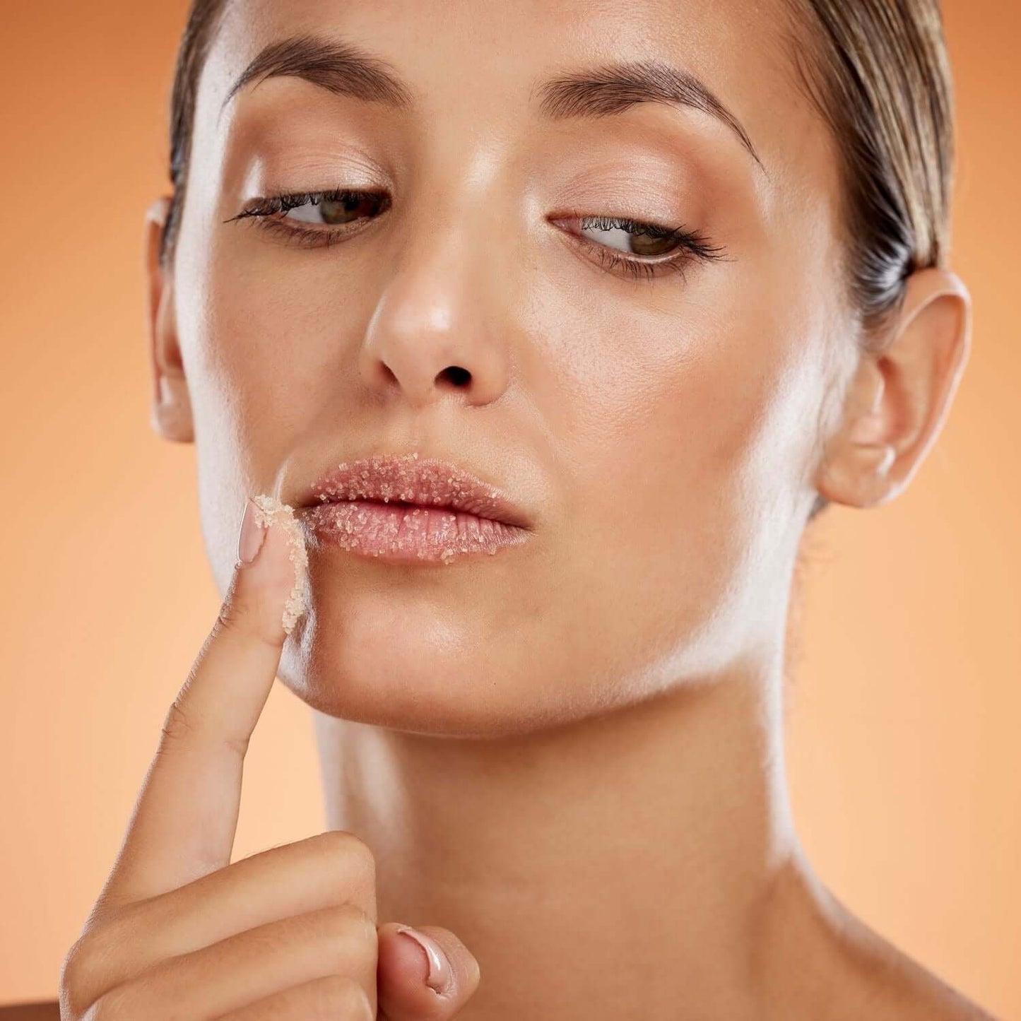Woman applying lip scrub from the Lip Care Deluxe Bundle for soft and healthy lips.