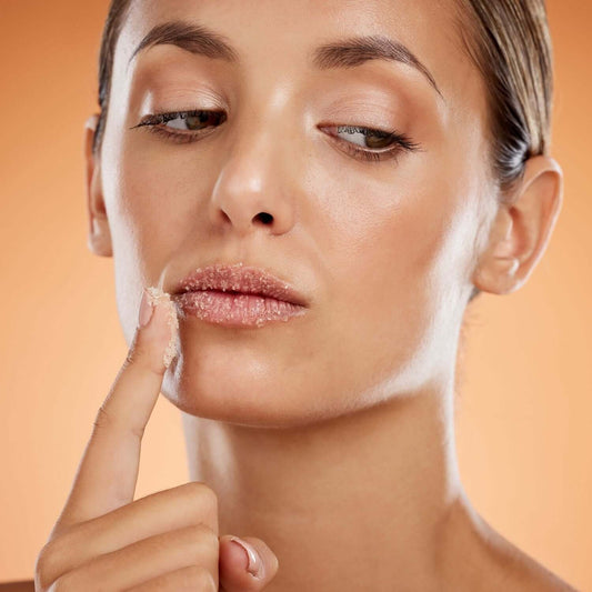 Woman applying lip scrub from the Lip Care Deluxe Bundle for soft and healthy lips.